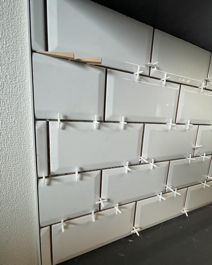 Flis settes med flisekryss på ferdig avrettet vegg